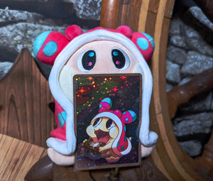 Snugooi plush from Lockstin & Gnoggin's Lockemon series, posed with its holographic collectible card. The sea slug character is depicted in its signature pink and blue hood, making it a highly sought-after plush for Lockemon fans.