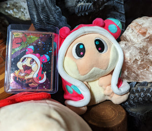 Snugooi plush from Lockstin & Gnoggin's Lockemon series, shown alongside its collectible card. The sea slug-inspired plush features pink, blue, and cream details, making it a must-have for fans of the Lockemon universe.