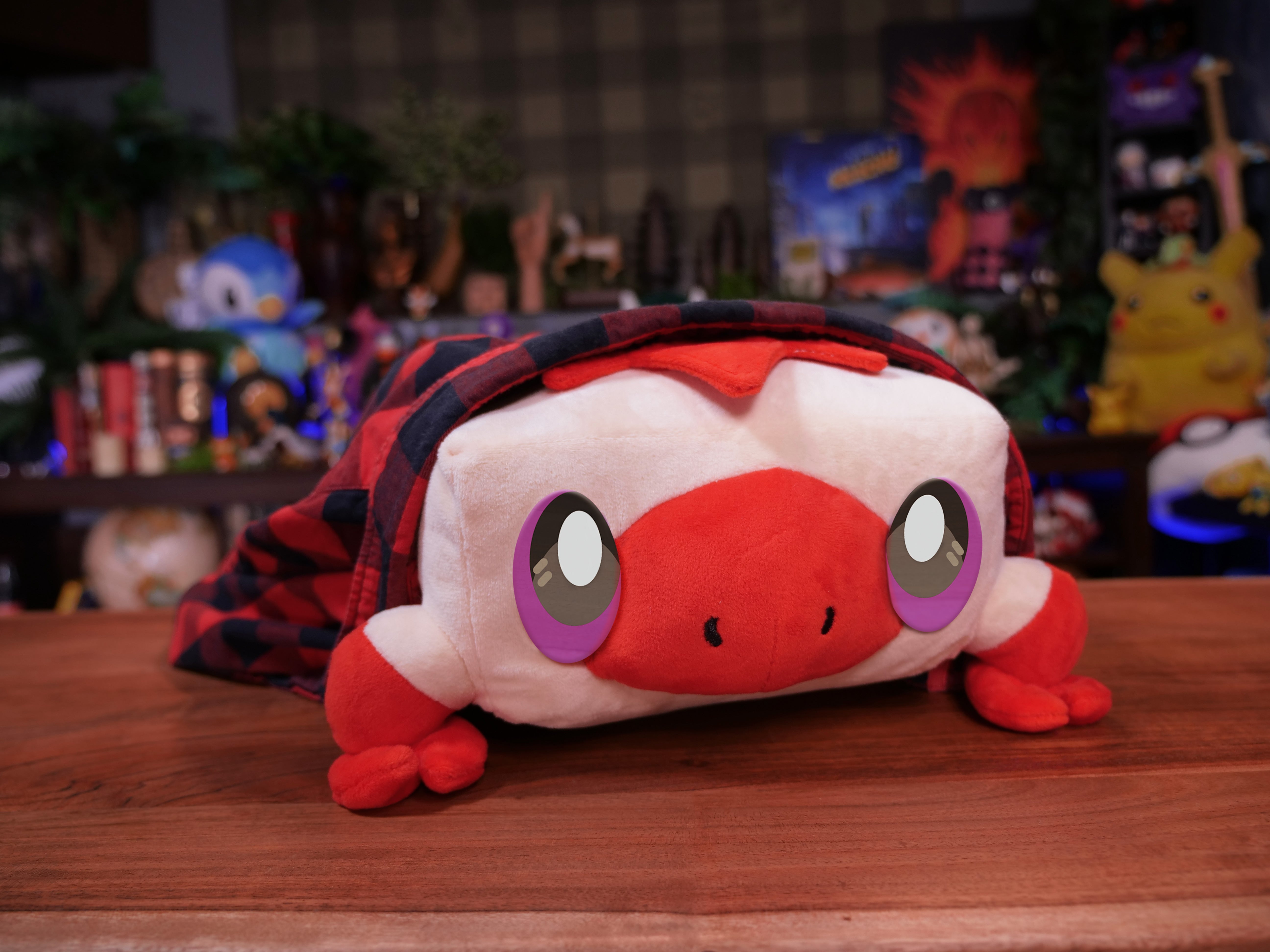 Front view of the Torfrug plush from Lockstin & Gnoggin's Lockemon series. This adorable tofu frog character features red and white colors, large purple eyes, and a cozy plaid blanket, making it a unique collectible for Lockemon fans.