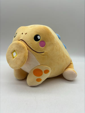 Angled view of TOTYM's Jin Chan frog plush, featuring its soft beige body, orange spots, blue accents, and adorable face. Kawaii mythical creature plush perfect for collectors.